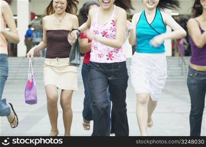 Mid section view of a group of young women running with shopping bags