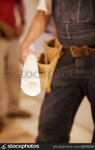 Mid section view of a male architect holding a blueprint