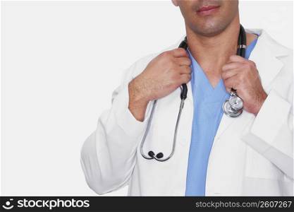 Mid section view of a male doctor holding a stethoscope around his neck