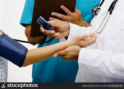 Mid section view of a male doctor measuring blood pressure of a female patient
