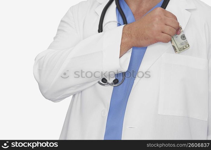 Mid section view of a male doctor putting dollar bills into his pocket