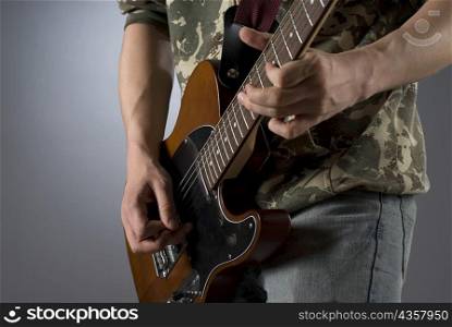 Mid section view of a male guitarist playing a guitar