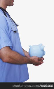 Mid section view of a male nurse holding a piggy bank