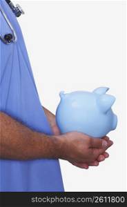 Mid section view of a male nurse holding a piggy bank