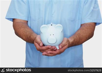 Mid section view of a male nurse holding a piggy bank