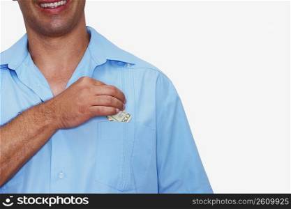 Mid section view of a male nurse putting a dollar bill into his pocket