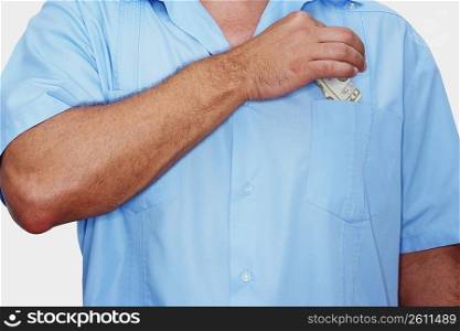 Mid section view of a male nurse putting a dollar bill into his pocket