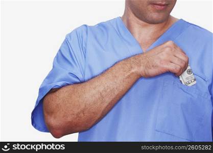Mid section view of a male nurse putting paper currency in his pocket