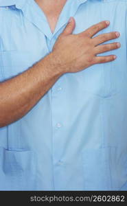 Mid section view of a male nurse with his hand on his chest