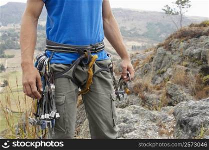 Mid section view of a male rock climber with climbing equipments around his waist