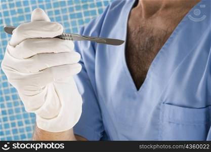 Mid section view of a male surgeon holding a scalpel