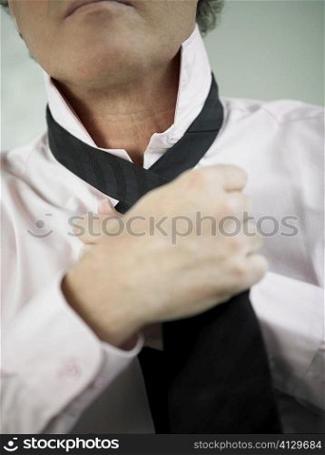 Mid section view of a man adjusting his tie