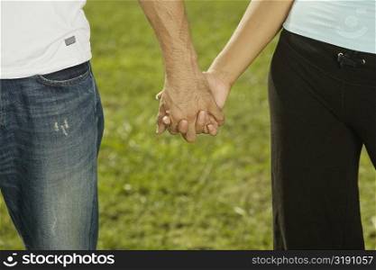 Mid section view of a man and a woman holding hands