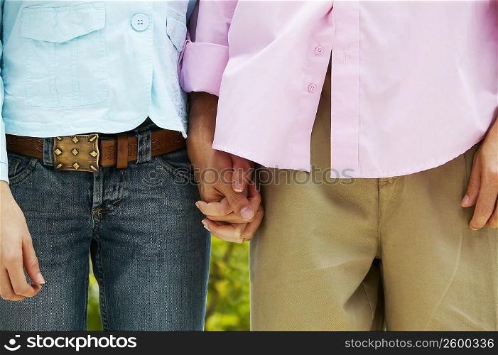 Mid section view of a man and woman standing and holding hands