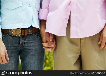 Mid section view of a man and woman standing and holding hands