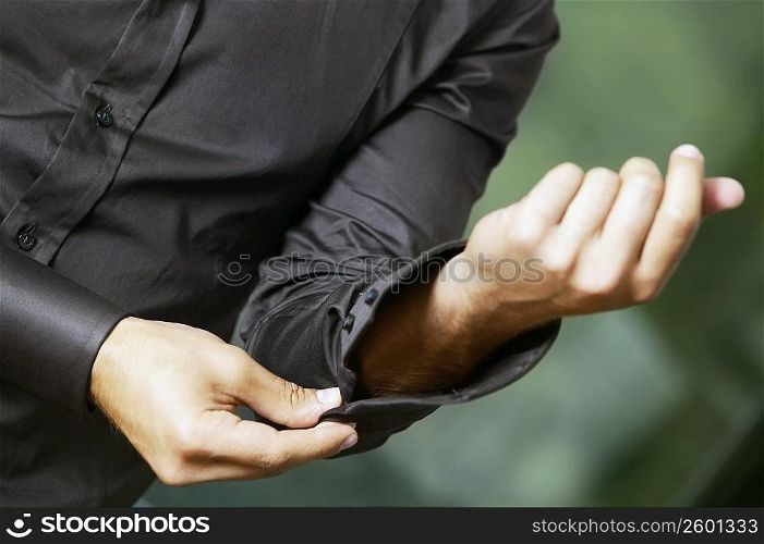 Mid section view of a man buttoning his cuff