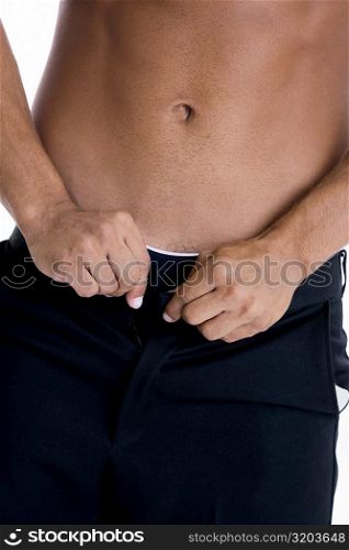 Mid section view of a man buttoning his pants