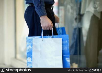 Mid section view of a man carrying shopping bags