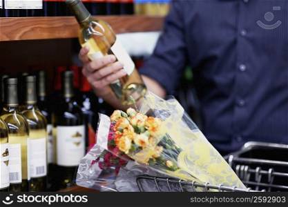 Mid section view of a man choosing a bottle of wine in a supermarket