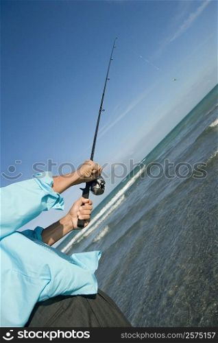 Mid section view of a man fishing in the sea