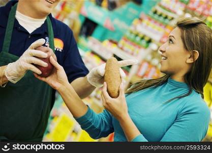 Mid section view of a man giving raw potatoes to a young woman