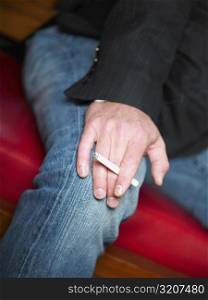 Mid section view of a man holding a cigarette