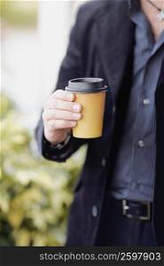 Mid section view of a man holding a disposable cup