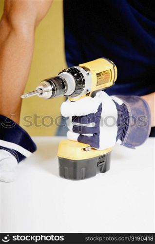 Mid section view of a man holding a drill machine