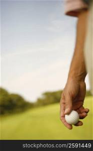 Mid section view of a man holding a golf ball