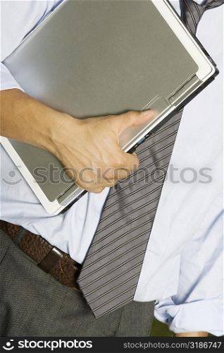 Mid section view of a man holding a laptop