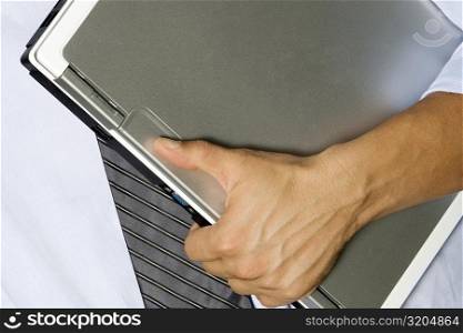 Mid section view of a man holding a laptop