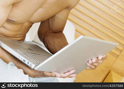 Mid section view of a man holding a laptop