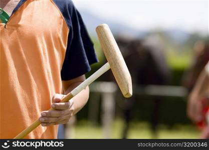 Mid section view of a man holding a polo mallet