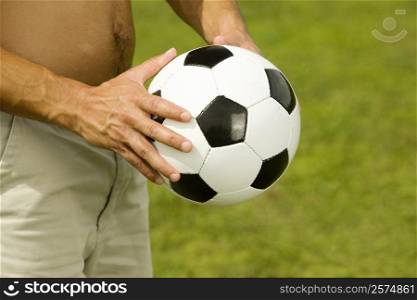 Mid section view of a man holding a soccer ball