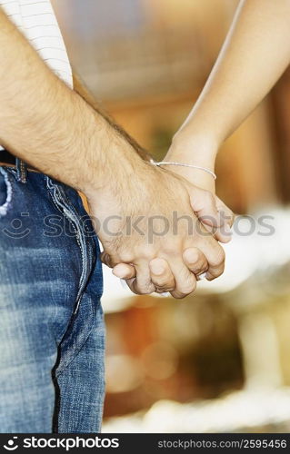 Mid section view of a man holding a woman&acute;s hand