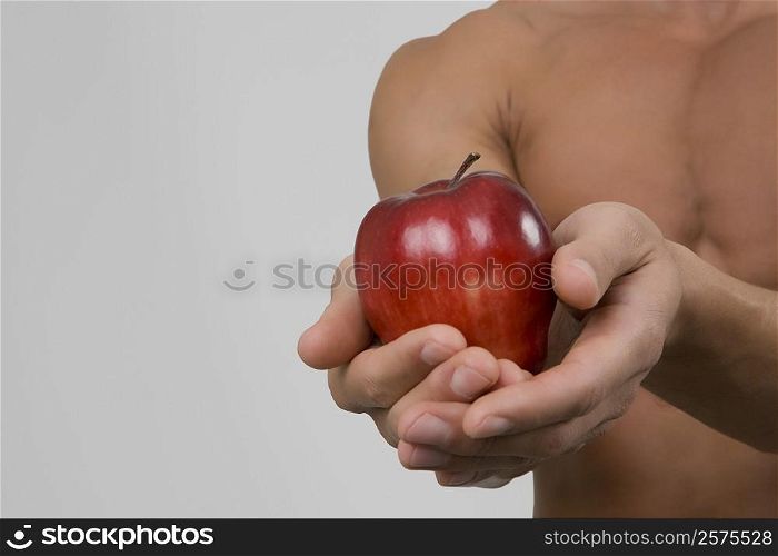 Mid section view of a man holding an apple
