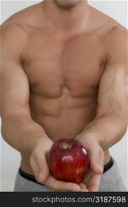 Mid section view of a man holding an apple