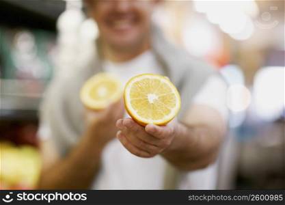 Mid section view of a man holding two pieces of orange