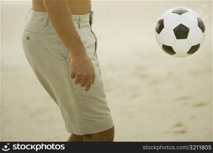 Mid section view of a man playing with a soccer ball