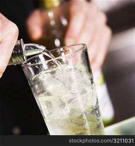 Mid section view of a man pouring alcohol into a glass filled with ice