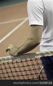 Mid section view of a man standing beside a tennis net