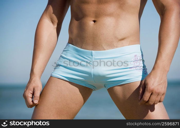 Mid section view of a man standing on the beach