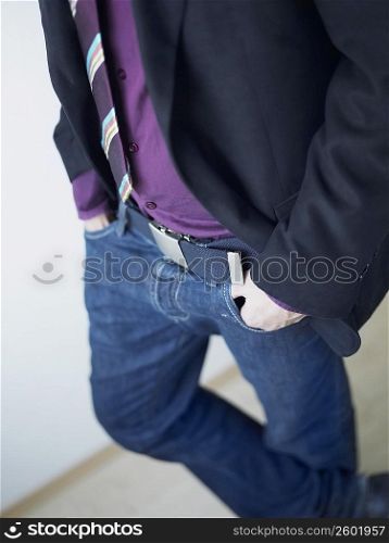 Mid section view of a man standing with his hands in his pockets