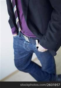 Mid section view of a man standing with his hands in his pockets