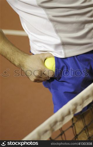 Mid section view of a man taking out a tennis ball from his pocket