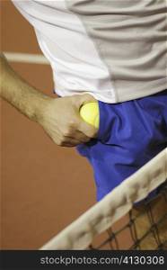 Mid section view of a man taking out a tennis ball from his pocket