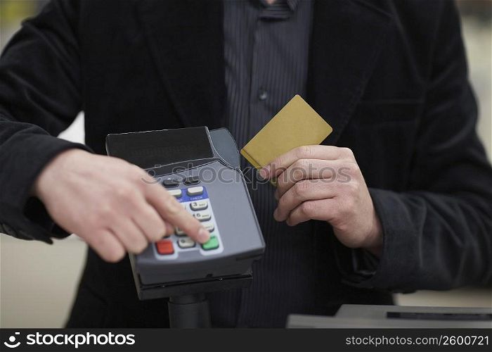 Mid section view of a man using a credit card reader