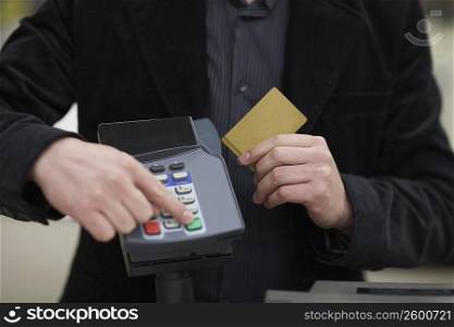 Mid section view of a man using a credit card reader