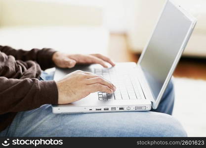 Mid section view of a man using a laptop