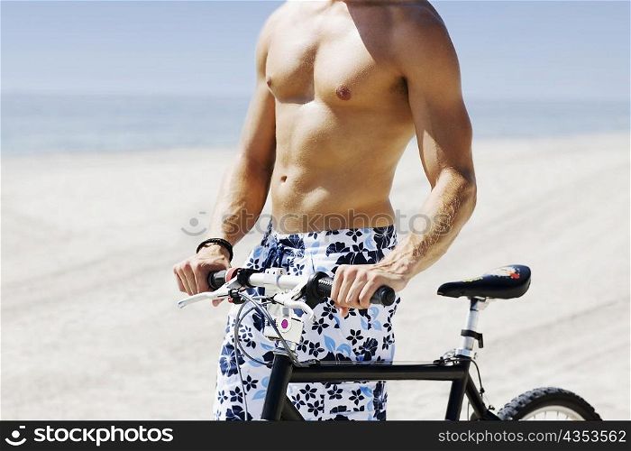 Mid section view of a man with a bicycle on the beach